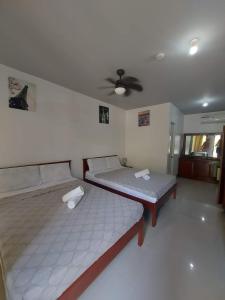 two beds in a room with a ceiling fan at Garden Village Resort in Moalboal