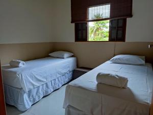 two beds in a room with two windows at Casa Azul Perequê in Ilhabela