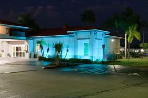 a white house with palm trees in a parking lot at Rodeway Inn Sun City Center in Sun City Center