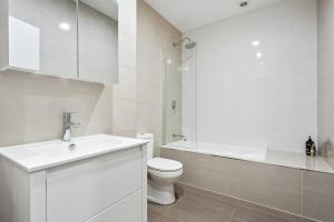 een witte badkamer met een toilet en een wastafel bij Kiama Coastal Haven in Kiama
