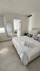 a white bedroom with a large bed with two towels on it at Cimarron Suites Playa Parguito in Aricagua