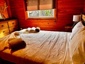 Una cama en una habitación de madera con toallas. en Vila Emigrante en Capelas
