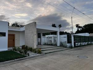 een wit huis met een hek en palmbomen bij villa green paradise in San Felipe de Puerto Plata
