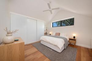 a white bedroom with a bed and a ceiling fan at The Victorian Secret in Flemington in Melbourne