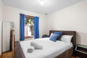 um quarto com uma cama com cortinas azuis e uma janela em Price on the Beach 2c em Torquay