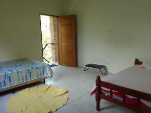 a bedroom with two beds and a door to a doorway at Suítes Recanto Dos Passarinhos 2 in Ubatuba