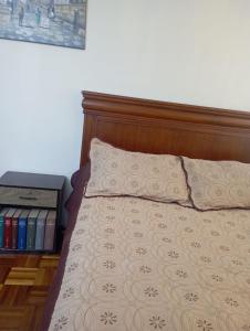 a bed with a wooden head board and two pillows at Habitación acogedora in Quito