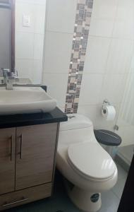 a bathroom with a white toilet and a sink at Habitación acogedora in Quito