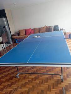 a blue ping pong table in a room with a couch at Habitación acogedora in Quito