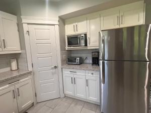 cocina con armarios blancos y nevera de acero inoxidable en 2 Bedroom Suite with Full Kitchen ( Sweet Home Rental), en Revelstoke