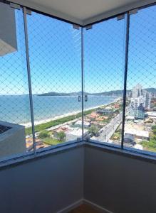 a room with a large window with a view of the ocean at Ap 154 Balneário Piçarras in Piçarras