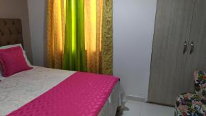 a bedroom with a bed with a pink and green curtain at Loft urbano apartamento in Salento