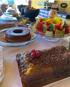 a table topped with plates of cake and fruit at Pousada Engenho Velho in Serra do Cipo