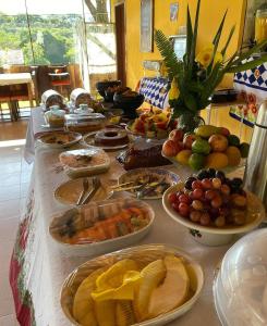 a long table with many plates of food on it at Pousada Engenho Velho in Serra do Cipo