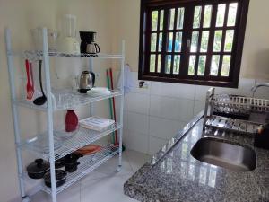 kuchnia ze zlewem i półką z przyborami kuchennymi w obiekcie Casa Azul Perequê w mieście Ilhabela