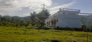 um edifício branco no lado de um campo em Vedic Farms em Garhshankar