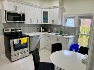 a kitchen with white cabinets and a table and a stove at Luxury Suite with King Bed-4 minutes to The Falls in Niagara Falls