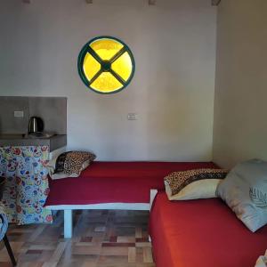 een kamer met een rode bank en een klok aan de muur bij Níspero in San Marcos Sierras