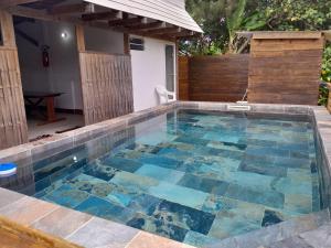 a swimming pool with blue tiles on top of it at Mara'ai le spot Tubuai, Chambre Triple Deluxe Mahu SDB Privée avec piscine in Tubuai
