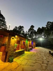 a building with a stone courtyard at night at Pine View StayHome in Pauri
