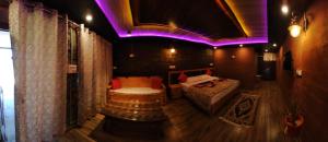 a room with a bed and a couch and purple lights at Nature Villaas BASA HOMESTAY in Pauri