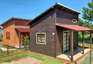 uma pequena casa de madeira com um telhado vermelho em Chalé Tribos Livres em Torres