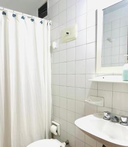 een witte badkamer met een douchegordijn en een toilet bij Confortable & estiloso departamento en la ciudad de Mendoza in Mendoza