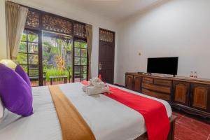 a bedroom with a bed with a teddy bear on it at Puri Mango Guest House Sanur in Sanur