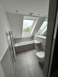 a bathroom with a toilet and a sink and a window at The Penthouse Double Bedroom for Rent Use of kitchen in Epsom