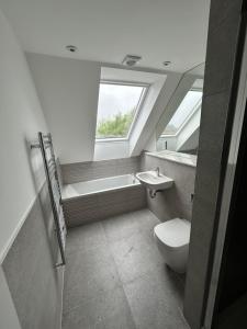 a bathroom with a toilet and a sink and a window at The Penthouse Double Bedroom for Rent Free Parking in Epsom