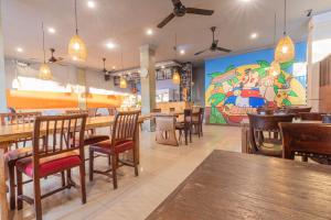a restaurant with wooden tables and chairs and a large mural at Puri Mango Guest House Sanur in Sanur