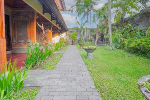 a walkway in front of a building with plants at Puri Mango Guest House Sanur in Sanur