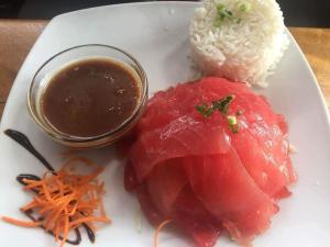 un plato de comida con carne y arroz y una salsa en Mara'ai le spot Tubuai Chambre triple Taahueia Deluxe SDB privée avec piscine en Tubuai