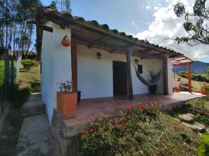 a cottage with a porch in a garden at Siskua Alojamiento rural in Boyacá
