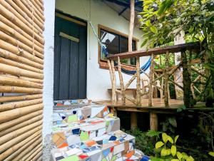 een veranda met een hangmat en een terras met tegels bij Finca Flora del Rio, Habitacion Las Orquideas in Pijao