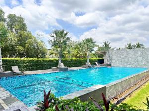 uma piscina numa villa com palmeiras em Herma Hotel em Samutprakarn