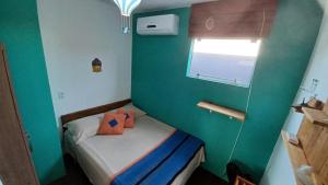 a small green room with a small bed with orange pillows at Hostel Tribos Livres in Torres