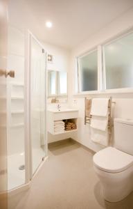 a white bathroom with a toilet and a sink at Casino Court Motor Lodge in Christchurch