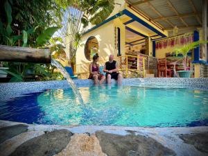 Ein Mann und eine Frau sitzen in einem Pool mit einem Brunnen in der Unterkunft Blue Moon Guesthouse in Puerto Princesa
