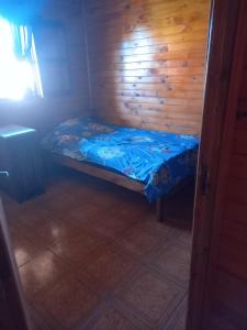 un piccolo letto in una camera con parete in legno di LA CABAÑA DE SERGIO a Gobernador Roca