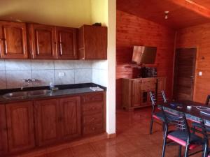 a kitchen with wooden cabinets and a table with chairs at LA CABAÑA DE SERGIO in Gobernador Roca