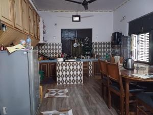 a kitchen with a table and a refrigerator at Bardiya Eco Safari Homestay in Bhurkīā