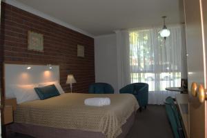 um quarto com uma cama e uma parede de tijolos em City Gardens Motel em Traralgon