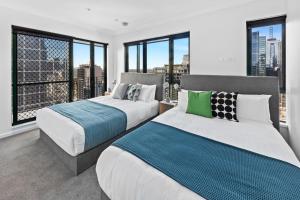 two beds in a room with large windows at Regency Towers in Melbourne