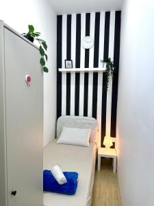ドバイにあるStriped Partition Room in Barsha 1 Near Mall of the Emiratesの黒と白のストライプの壁の小さな客室で、ベッド1台が備わります。