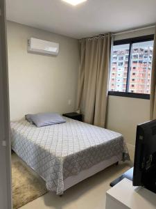 a small bedroom with a bed and a window at Excelente AP (novo) Praia Brava. in Itajaí