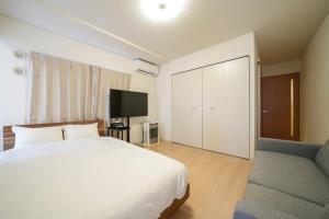 Residence Hotel Liberte في سابورو: غرفة نوم بسرير وتلفزيون وأريكة