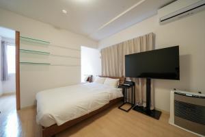 Residence Hotel Liberte في سابورو: غرفة نوم بسرير وتلفزيون بشاشة مسطحة