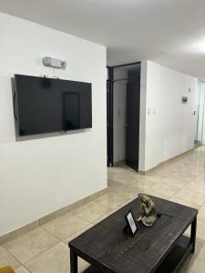 Zimmer mit einem Tisch und einem TV an der Wand in der Unterkunft Ica tierra del sol eterno 1 in Ica