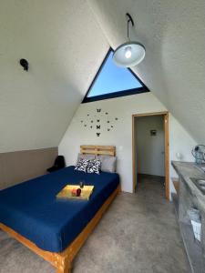 Schlafzimmer mit einem blauen Bett und einem großen Fenster in der Unterkunft Cabaña Encino Saúco in Malinalco